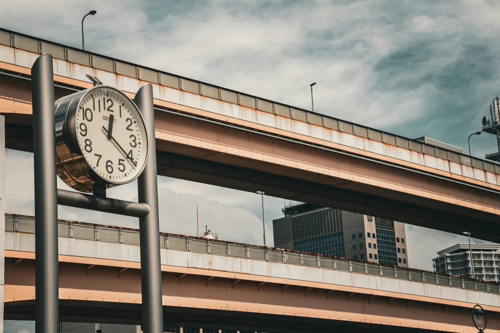 City clock beside elevated highways — official time in Japan in real time