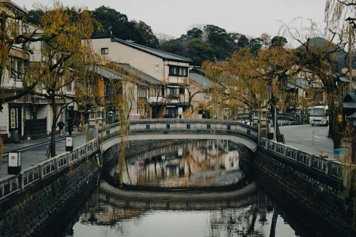 Kinosaki canal with a stone bridge and willows reflected in the water