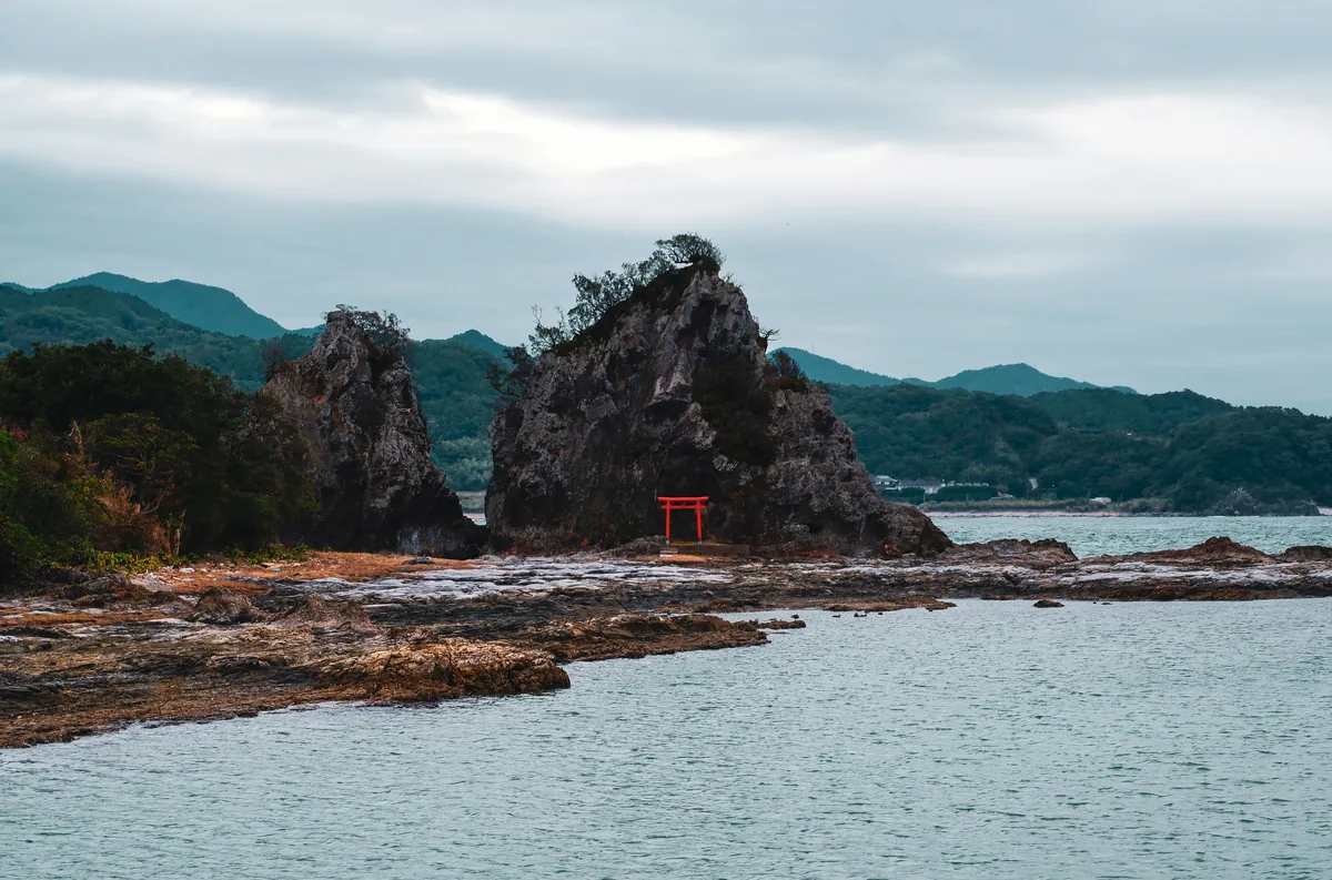 Small red torii among rock formations facing the sea on the Wakayama coast